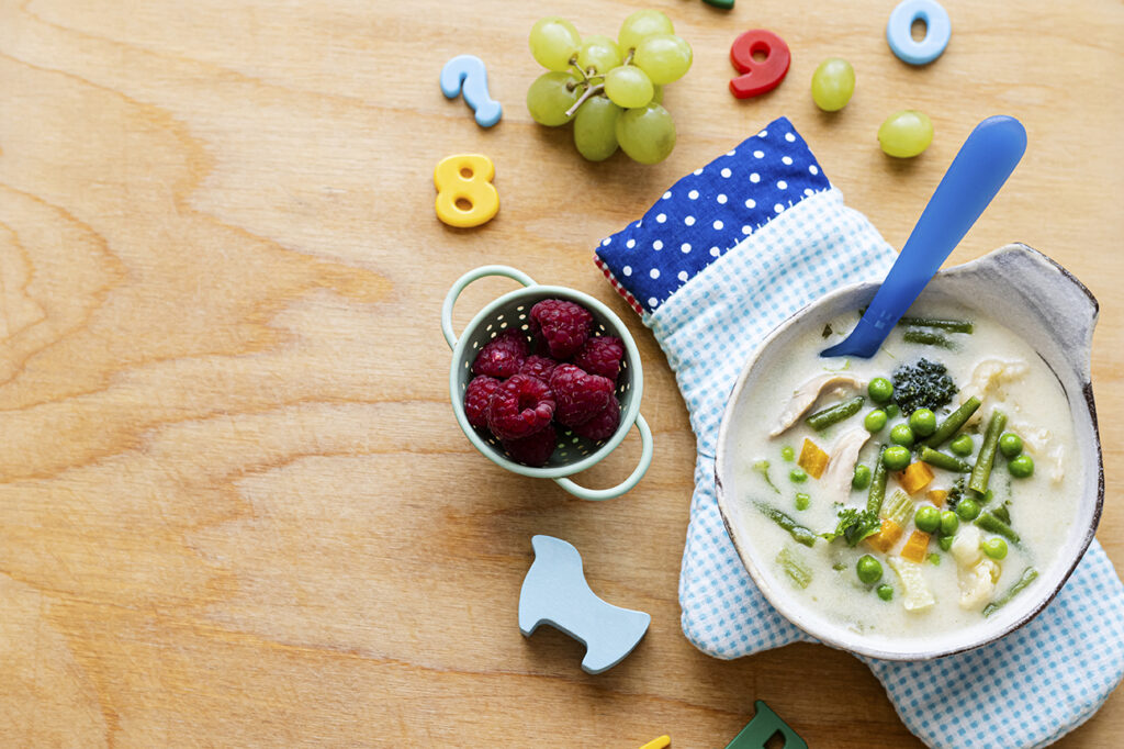 Kindgerechtes Mittagessen für Kitas und OGS in Meckenheim: Gemüsesuppe mit Erbsen, Karotten und Hähnchen, dazu frische Himbeeren und Trauben